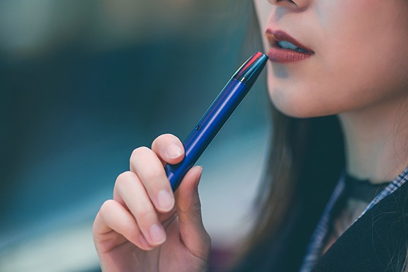 Closeup of a woman holding a handheld vaporizer with cartridge, legally available about legalization 2.0